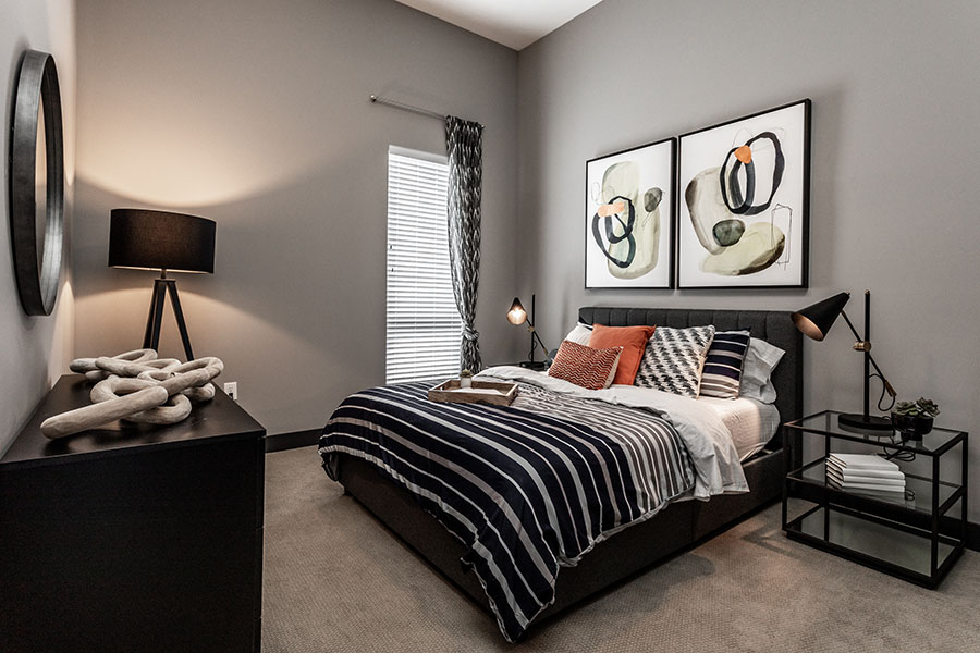Contemporary bedroom with grey paint, lamps, and wall art.